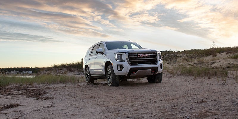 A 2024 GMC Yukon parked on a dirt road, showcasing its rugged design and off-road capabilities.